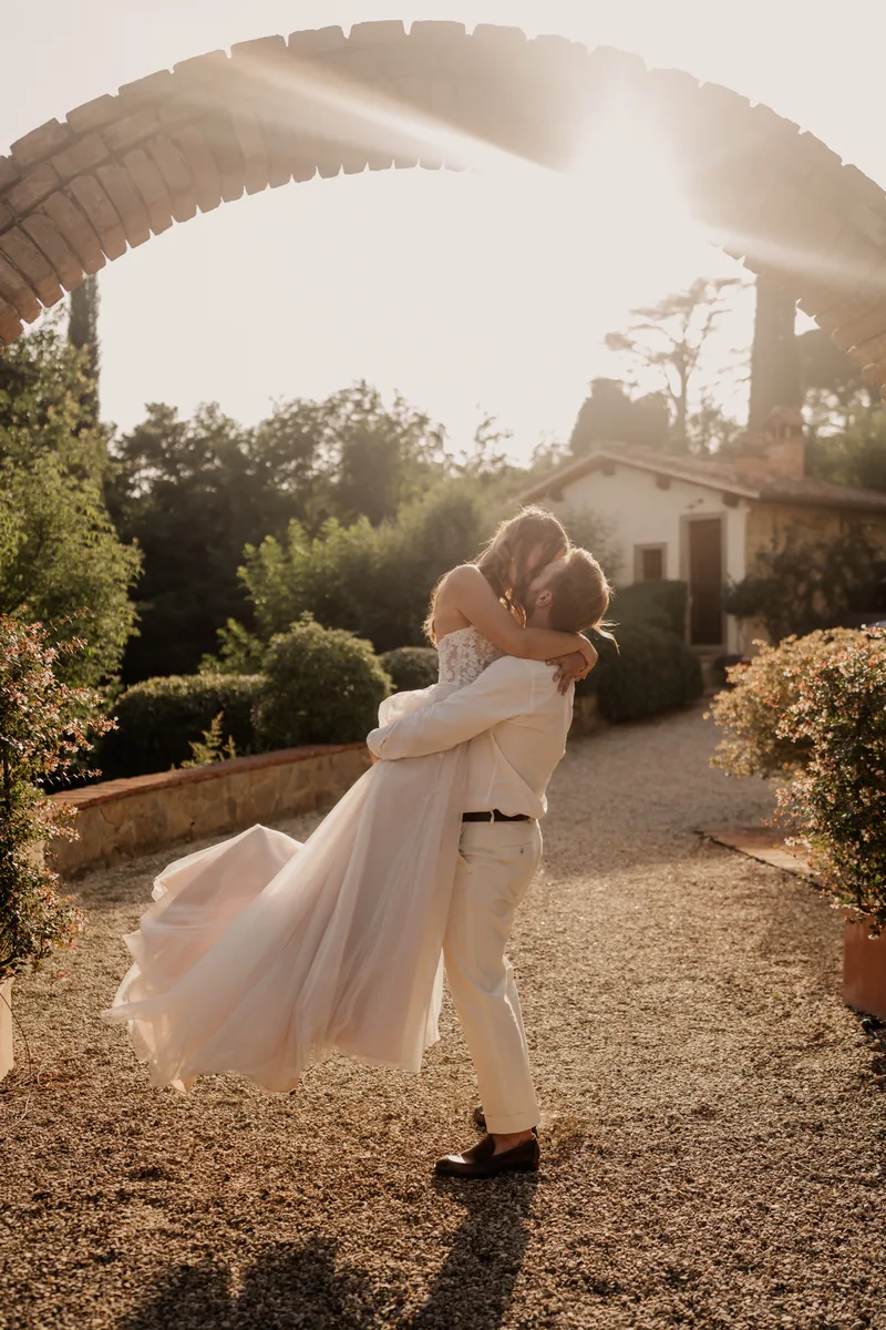 Couple kissing under the brick arch at sunset — intimate wedding in Tuscany at Il Podere di Toscana